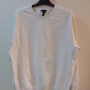 Vit sweatshirt - Säljer en klassisk vit sweatshirt i normal passform. Perfekt för både vardag och chill hemma. Den har långa ärmar och är gjord i mjukt material för extra komfort. Ett måste i garderoben för en enkel och stilren look.