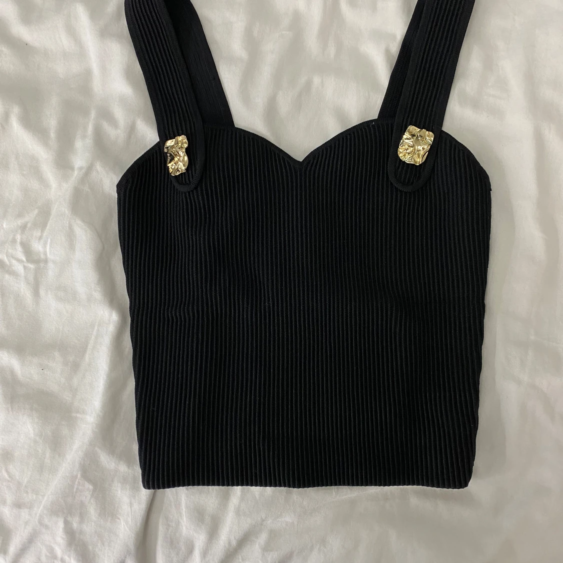 Svart ribbad topp med gulddetaljer