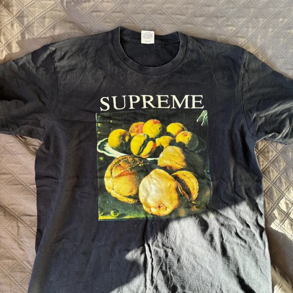 Säljer en svart Supreme t-shirt i 100% bomull med ett coolt fruktmotiv på framsidan. Perfekt för vardagsbruk eller att styla upp för en avslappnad fest. T-shirten är i bra skick och har en normal passform. Passa på att köpa denna unika piece! 🍑. T-shirts.