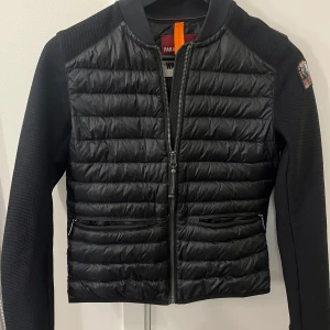 Svart jacka från Parajumpers - Säljer en snygg svart jacka från Parajumpers i mycket bra skick. Jackan har en quiltad design med dragkedja framtill och långa ärmar. Perfekt för höst och vår, och den är både stilren och funktionell. Märkeslogga på ärmen ger en extra touch av stil. Ny pris på jackan är ca 3000kr. Priset kan diskuteras vid snabb affär!