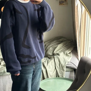 Mörkblå tröja från sweet sktbs  - Säljer en mörkblå tröja från Sweet Sktbs med ett coolt abstrakt ansiktsmönster i svart. Tröjan är i bra skick och har en normal passform med långa ärmar. Perfekt för höst och vinter! 🌀