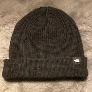 Svart mössa från The North Face - Säljer en svart mössa från The North Face. Den är i nytt skick och perfekt för kalla dagar. 🍂Mössan är jätteskön och jättemjuk. Köptes från Zalando och aldrig använd. Passar både höst och vinter. Perfekt för dig som vill hålla stilen samtidigt som du håller dig varm! Skriv för fler bilder eller frågor och funderingar! 🍁