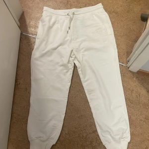 Vita mjukisbyxor från GANT - Säljer ett par vita mjukisbyxor från GANT i mycket bra skick. De har en bekväm passform med dragsko i midjan och ribbade muddar vid bensluten. Den är helt oanvänd.