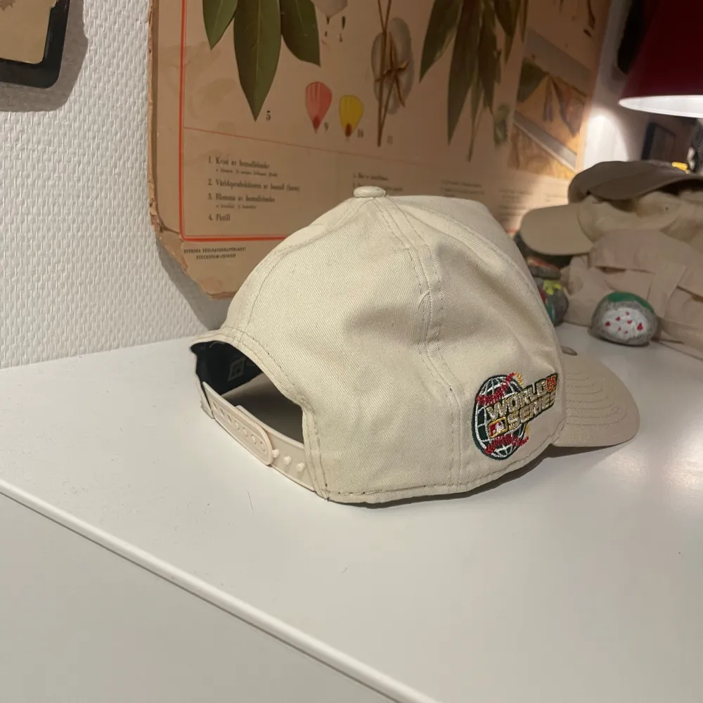 Säljer en beige keps från New Era med en snygg broderad logga på framsidan. Kepsen har en justerbar rem baktill och en cool World Series-märke på sidan. . Accessoarer.