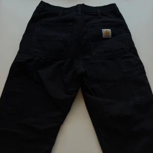 Svarta byxor från Carhartt - Nästan helt oanvända Carhartt byxor/jeans. Nypris 1200kr. Mitt pris 750 kan gå ner vid snabb affär. Storlek 28/32. DM för fler frågor