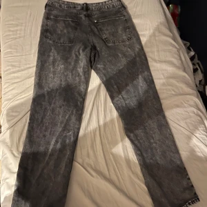 Grå jeans från H&M - Säljer ett par grå jeans från H&M i storlek M. De har en relaxed fit och är perfekta för en casual look. Jeansen har en klassisk femficksdesign och är i bra skick. Perfekta för både vardag och avslappnade tillfällen.