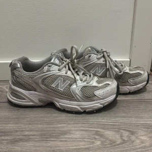 Grå New Balance sneakers - Säljer ett par grå New Balance 530 sneakers i bra skick. De har en klassisk design med snörning och är perfekta för träning eller vardagsbruk. Skorna har en bekväm passform och är gjorda i syntetmaterial med meshdetaljer för bra ventilation.