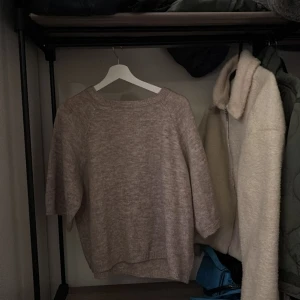 Beige stickad tröja från 157 - Mysig beige stickad tröja från 157. Perfekt för kyliga dagar med sin mjuka och bekväma passform. Tröjan har långa ärmar och en rund halsringning.