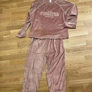 Rosa velourset från Mihra - Mysigt rosa velourset från Mihra med texten 'We are fighter, never give up' på tröjan. Använd tre gånger