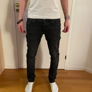 Mörkgrå jeans från Jack&Jones - Ett par snygga mörkgrå slim jeans från Jack&Jones i modell Glenn. Storlek 28/32. Använda 2 gånger och nyinköpta i November. Nypris 699kr. Personen på bilden är 177 cm lång och väger 65 kg. Skriv för frågor!