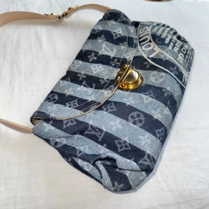 Axelväska med mönster Louis Vuitton  - Snygg axelväska med ett unikt mönster i blå och grå toner. Väskan har en justerbar axelrem i beige och en säker stängning med ett metallspänne. 