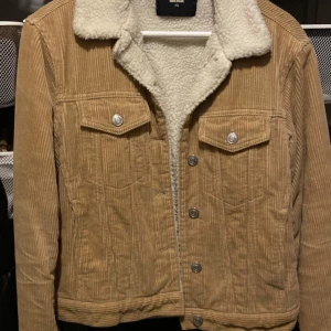 Beige manchesterjacka från Bik Bok - Säljer en snygg beige manchesterjacka från Bik Bok i storlek XS. Jackan har en mysig teddyfoderkrage och knappar framtill. Perfekt för höst och vår!