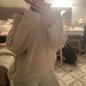 Beige stickad tröja med rosett - Mysig beige stickad tröja med en söt rosett i ryggen. Tröjan har en loose passform och långa ärmar, perfekt för kyliga dagar. Den ribbade strukturen ger extra stil och komfort. Den är i strl lx men skulle säga att den passar mer som en m och passar jättebra på mig som oftast har s-m. Lite nopprig och små skavanker som enkelt går att laga (se sista bild) annars superfin. 