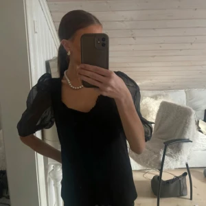 Svart blus från Bubbleroom - Elegant svart blus från Bubbleroom med puffiga transparenta ärmar och en stilren design. Perfekt för en chic look.