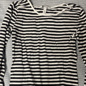 Svartvit randig tröja från H&M - Säljer en klassisk svartvit randig tröja från H&M. Tröjan har långa ärmar och en rund halsringning, perfekt för en stilren look. 