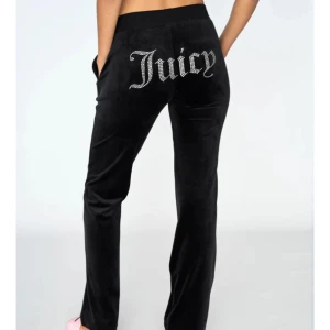 Svarta velourbyxor från Juicy Couture - Snygga svarta velourbyxor från Juicy Couture med glittrande text på baksidan. Perfekta för en avslappnad och trendig look. Jättebra och inga nedtrampningar💕 skriv för bilder jag tar själv🥰