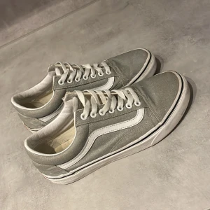 Grå sneakers från Vans - Snygga grå sneakers från Vans med klassisk vit sidosymbol och snörning. Perfekta för en avslappnad stil. Skorna har en vit sula med svart rand som ger en tidlös look. Pris kan diskuteras vid snabb affär. 🏬 