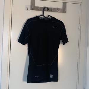 Säljer en svart Nike Pro Combat Dri-Fit t-shirt i kompressionsmodell. Perfekt för träning med sin fukttransporterande teknik. T-shirten har korta ärmar och en diskret Nike-logga på bröstet. Ge gärna bud och prisförslag!