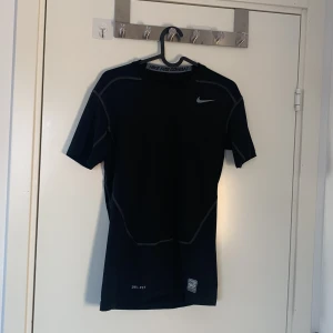 Svart Nike compression shirt - Säljer en svart Nike Pro Combat Dri-Fit t-shirt i kompressionsmodell. Perfekt för träning med sin fukttransporterande teknik. T-shirten har korta ärmar och en diskret Nike-logga på bröstet. Ge gärna bud och prisförslag!