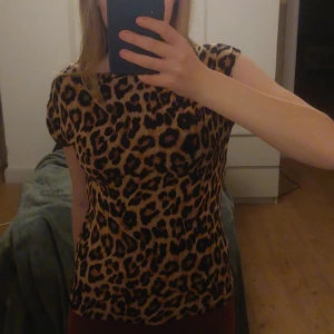 Leopardmönstrad topp  - Snygg leopardmönstrad topp från The Beachline Collection i storlek S. Toppen har korta ärmar och en figurnära passform, perfekt för att sticka ut i mängden. 🐆