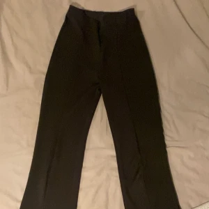 Svarta byxor med slits - Snygga svarta byxor med slits vid bensluten. Perfekta för en stilren look. De har en rak passform och är tillverkade i ett mjukt material som ger en bekväm känsla.