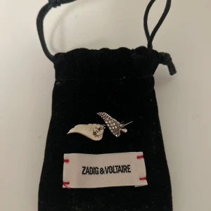 Silverfärgade örhängen från Zadig & Voltaire - Jättefina silverfärgade örhängen från Zadig & Voltaire i form av änglavingar, i mässing och dekorerade med glittrande stenar och stift. I nyskick och endast använda en gång. Skriv gärna till mig om du har några frågor! 💕