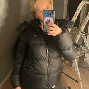 Svart pufferjacka från Calvin Klein - Snygg svart pufferjacka från Calvin Klein med dragkedja och hög krage. Jackan har långa ärmar och en stilren design, perfekt för kyligare dagar. Passar perfekt på både tjejer och killar! SOM NY! Pris kan diskuteras så tveka inte med att höra av dig! Nypris: 1500krk