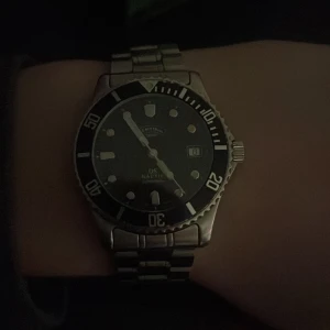 Certina DS Nautic - Snygg Certina klocka med rostfritt stålarmband och svart urtavla. Klockan har en klassisk dykarstil med datumvisning och tydliga markeringar. Perfekt för den som gillar en stilren och robust design. Klockan är från 1990 och därför finns synliga defekter. Lådan ingår även självklart. Var inte rädda att skriva och fråga om något. 