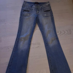 Blå bootcut jeans från JCL - Snygga blå bootcut jeans från JCL med slitna detaljer och dragkedjor vid fickorna. Perfekta för en avslappnad stil med en touch av edge. Midjemått rakt över: 40cm.  Benlängden rakt ner: 105cm💕💕