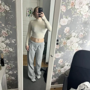 Beige croppad polotopp - Snygg beige croppad polotopp med långärmad design och öppen rygg. Perfekt för en trendig look.