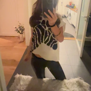 Isabelle bolduc - Säljer en cool vit topp med svart mönster. Toppen har en lös passform och korta ärmar, perfekt för en avslappnad stil.