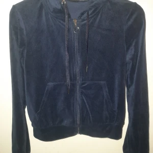 Mörkblå hoodie från Gina Tricot - Säljer en mörkblå hoodie från Gina Tricot i mjukt material. Den har dragkedja framtill och en praktisk huva med snörning. Perfekt för en avslappnad stil.