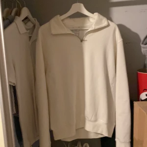 Vit tröja med dragkedja från Zara - Säljer en stilren vit tröja från Zara i storlek M. Den har en dragkedja framtill och är perfekt för en avslappnad look. ALDRIG ANDVÄND!!!