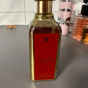 RIIFFS Ambre Rouge Perfume Water Unisex 100ml - Säljer en lyxig och förförisk unisexparfym från RIIFFS, Ambre Rouge. Den kommer i en elegant guld- och röd flaska som rymmer 100 ml. Doften är en gourmet, nischparfym med inslag av vita blommor och färska, saftiga frukter. Enbart testad🌸
