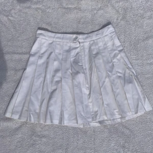 Tenniskjol - Vit tenniskjol från Bikbok. Fint fall. Storlek 42, passar typ M. Midjemått: 37 cm. Längd: 43 cm. Bra skick🤍