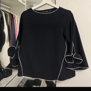 Marinblå blus trekvartsärmar  - Marinblå blus med trekvartsärmar, rosett detaljer på ärmarna. Mycket fint skick som ny.