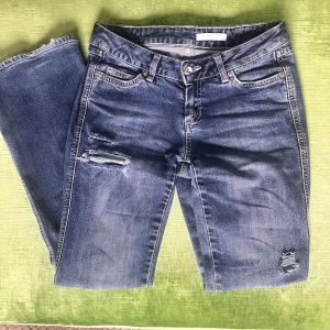 Lågmidjade jeans - Lågmidjade bootcut jeans med skitsnygga slitningar.  Midjemått 37cm, innerbenslängd 76cm