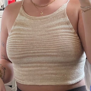 Beige stickad linne med snörning - Säljer en superfin beige stickad linne som är perfekt för sommaren. Den har en snygg snörning i ryggen och är ärmlös med en croppad passform. Perfekt för en dag på stranden eller en somrig fest! 🌞