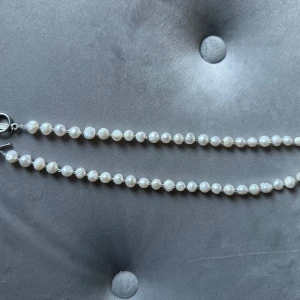 Vitt pärlhalsband med silverdetaljer - Säljer ett elegant vitt pärlhalsband med fina silverdetaljer. Halsbandet har en stilren design med runda pärlor och ett snyggt lås i silver. Perfekt för både vardag och fest! Storleken på pärlorna är ca 8 mm. Längd 45 cm. Nickelsäkert.