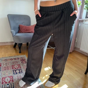 Randiga byxor från H&M - Säljer ett par snygga randiga byxor från H&M i storlek M. De är svarta med vita ränder och har en loose passform som ger en avslappnad stil. Perfekta för både vardag och fest. Materialet känns bekvämt och lätt, vilket gör dem idealiska för alla säsonger.