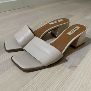 Beige klackskor från NA-KD - Säljer ett par snygga beige klackskor från NA-KD. De har en fyrkantig tå och en bred rem över foten 🤍