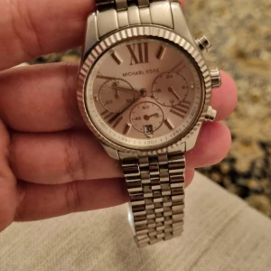 Silverfärgad klocka från Michael Kors - Säljer en stilren och elegant klocka från Michael Kors i silverfärg. Klockan har en klassisk design med romerska siffror på urtavlan och tre mindre urtavlor för extra funktioner. Armbandet är i rostfritt stål och har en robust känsla.