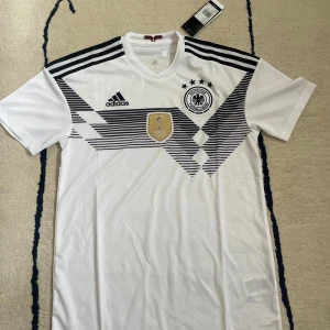 Tyskland Hemmatröja Vm - Säljer en äldre modell av Tysklands hemmatröja. Tröjan är helt oanvänd och alla tags etc finns kvar. Lag: 🇩🇪Namn: Inget Nummer: Inget  Condition: 10/10 (DS) Hör av dig för fler frågor