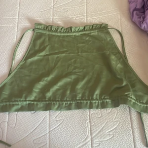 Grön halterneck topp från Shein - Säljer en snygg grön halterneck topp från Shein. Toppen är ärmlös och har en knytning i ryggen för en justerbar passform. Perfekt för sommardagar eller en festlig kväll!