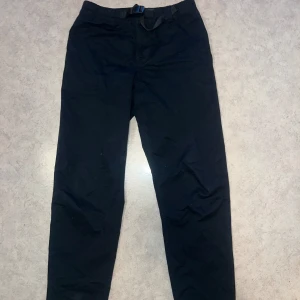 PEAK PERFORMANCE Byxor - Sjukt snygga svarta peakpreformance byxor, straight legged i storlek 30/32, helt oanvända. Byxorna kommer med inbyggt bälte. NY PRIS 900KR, MITT PRIS 99KR