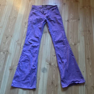 Lila lågmidjade bootcut jeans - Lila bootcut jeans med låg midja  Midjemått (mätt rakt över) 36-37cm Innerbenslängd: 79cm