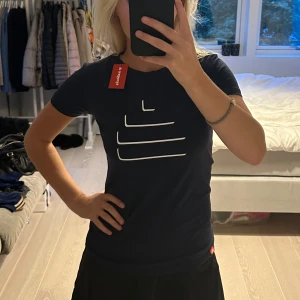 Svart t-shirt från Tyngre - Säljer en snygg mörkblå t-shirt från Tyngre i storlek S. Den har ett stilrent vitt mönster på framsidan och är gjord i ett mjukt och bekvämt material. Perfekt för både träning och vardag! 