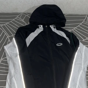 Corteiz jacka - En superfin och skön vindjacka, med reflex på armarna. Den är i storlek S men passar även bra för M. Perfekt nu för höst tiden då det blåser så mycket. Skicka ett dm för fler bilder.