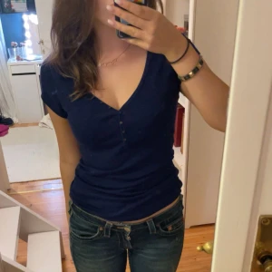 Mörkblå Henley-topp från Old Navy - Säljer en snygg mörkblå Henley-topp från Old Navy. Den har en v-ringad design med knappar framtill och korta ärmar. Perfekt för en casual look eller att klä upp med accessoarer. Toppen är i bra skick och superbekväm! Skriv för fler bilder!💜