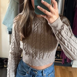 Croppad brun/beige kabelstickad tröja  - Säljer denna fina och mysiga tröja som passar perfekt nu till hösten. Använd ett fåtal gånger. Köparen står för frakten. 